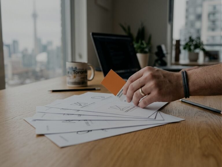 Printed brand sheets laid out on a desk with the Toronto skyline behind